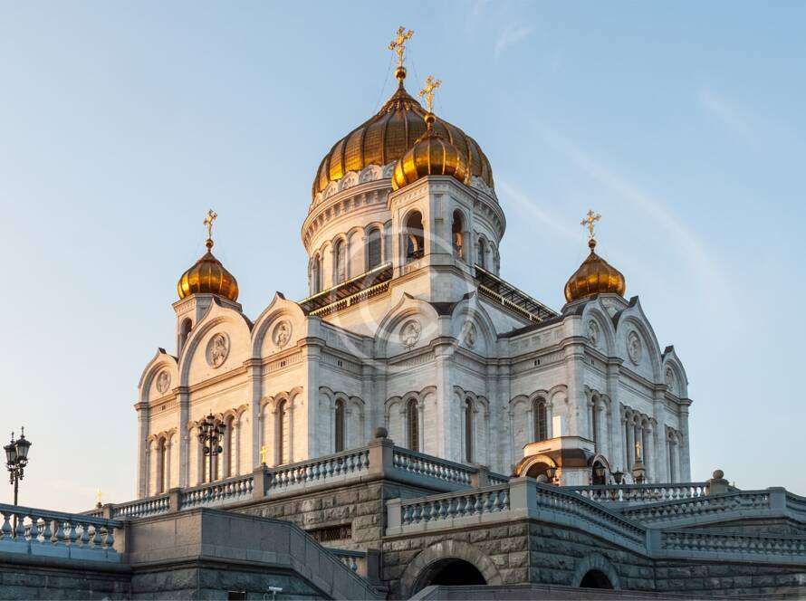 White stone cathedral with golden domes against a clear blue sky, showcasing intricate architectural details