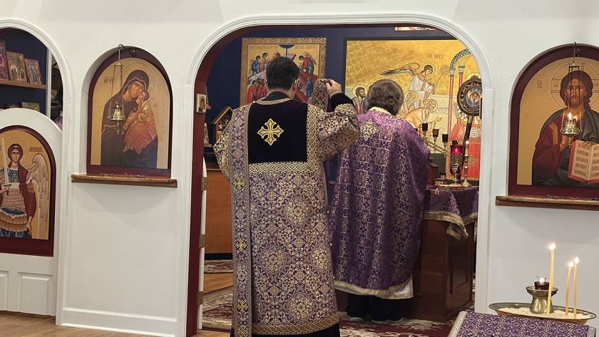 Priests in ornate robes during a religious service in an icon-adorned church interior