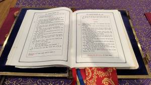 Open religious text on a lectern with ornate fabric and ribbon bookmarks