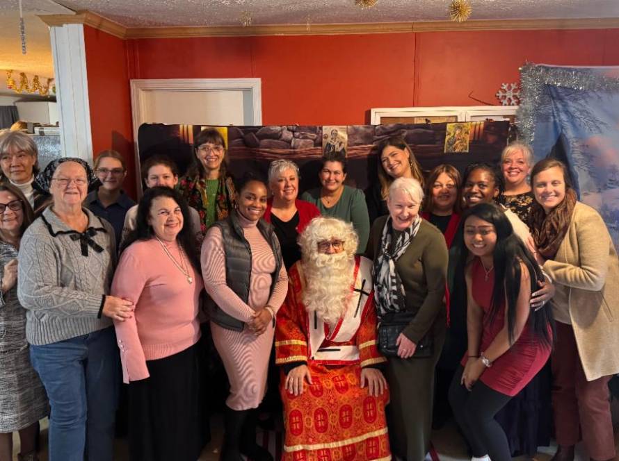 Group of smiling people posing with Santa Claus at a festive gathering indoors