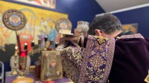 Priest in ornate purple robe conducting religious service at decorated altar