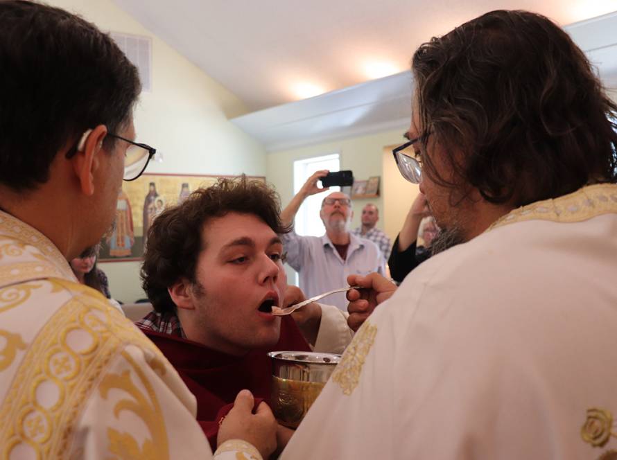 Priest administering Holy Communion to a parishioner in a church ceremony