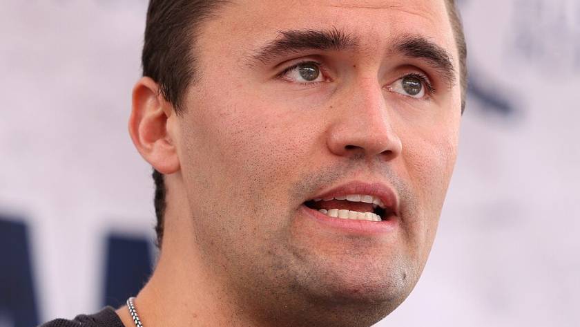 Man speaking into microphone at event, wearing black shirt, close-up image