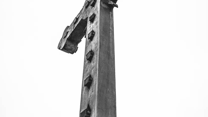Stone cross monument against a clear sky, symbolising faith and heritage in a monochrome photograph