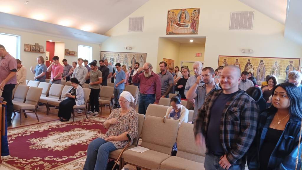 Congregation attending a church service in a chapel with religious icons on the walls