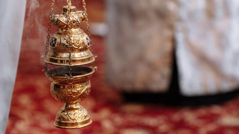 Golden incense burner with intricate designs in a church setting, suspended by chains, radiating tradition and ritual