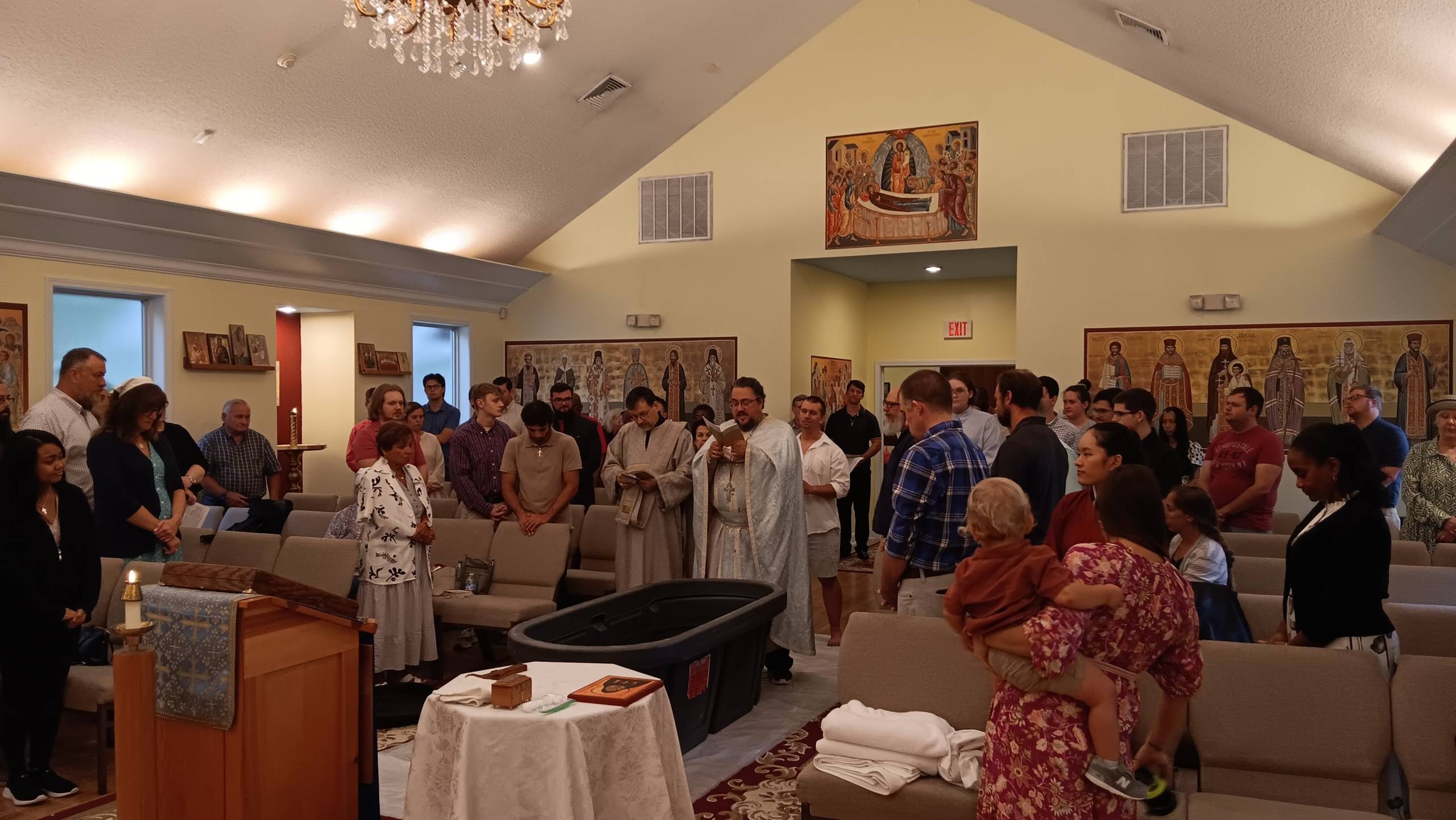 Community gathering inside a church for a special ceremony with icons and attendees in traditional attire