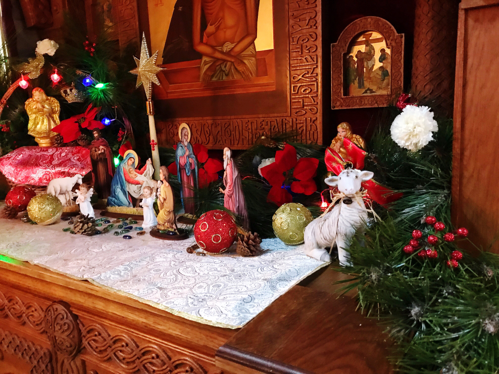 Festive Nativity scene with colorful lights, figurines, and Christmas decorations on a wooden altar