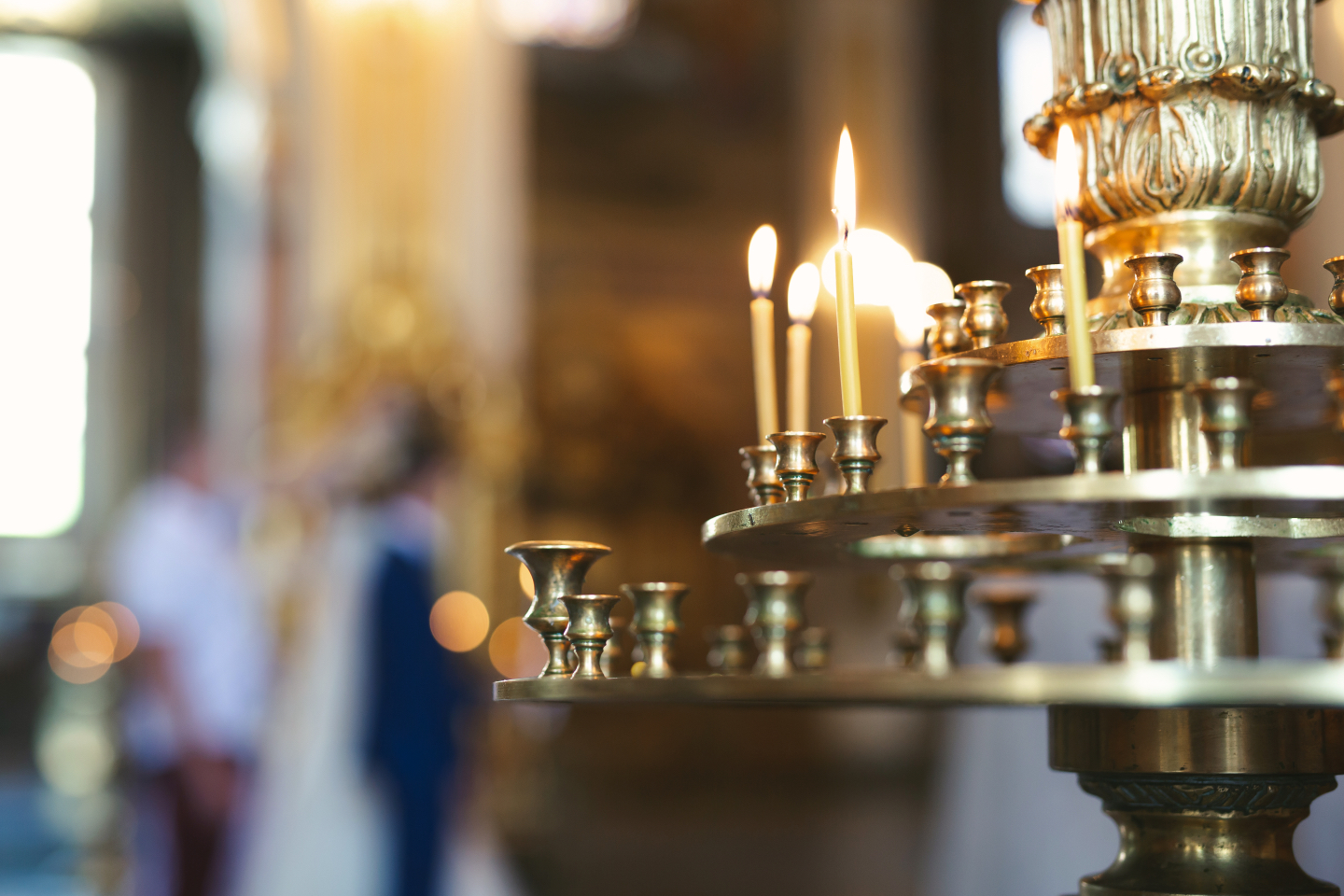 Golden candle holder with lit candles in a softly focused background of a cathedral interior