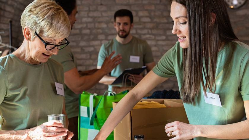 Volunteers sorting items for donation in a community center with boxes and canned goods visible