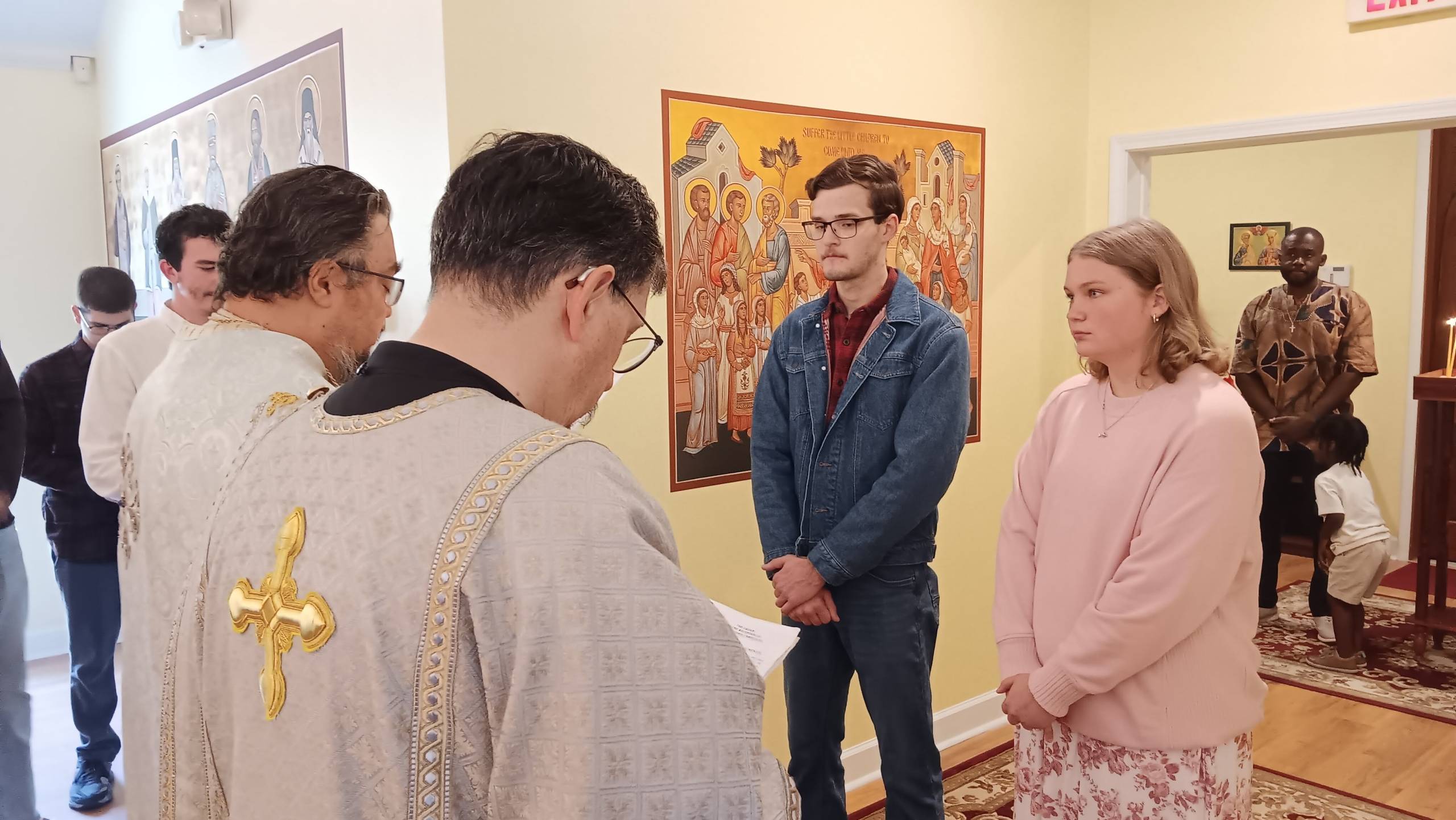 Religious ceremony with people gathered in church near iconographic art wall panel