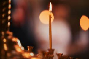 Lit candle in focus against a blurred warm background, creating a serene and cozy atmosphere