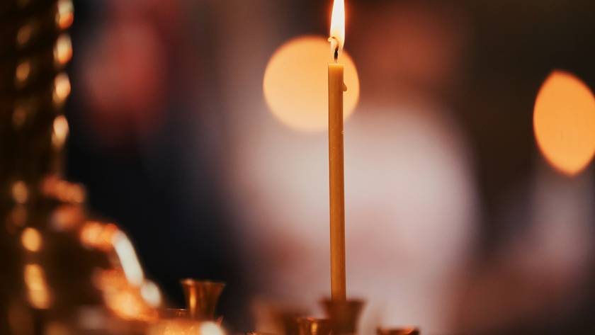 Lit candle in focus against a blurred warm background, creating a serene and cozy atmosphere