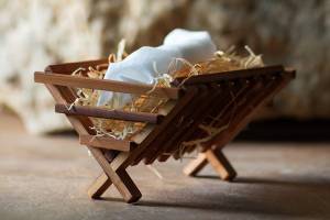 Wooden manger with straw and white cloth, symbolizing nativity scene or Christmas decoration in rustic setting