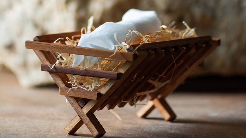 Wooden manger with straw and white cloth, symbolizing nativity scene or Christmas decoration in rustic setting