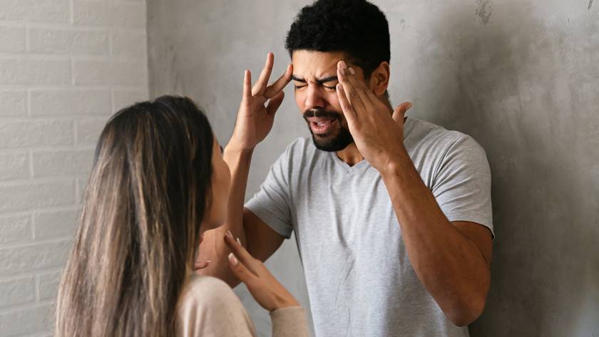 Couple having an argument, man frustrated and gesturing, woman facing him in a tense interaction at home