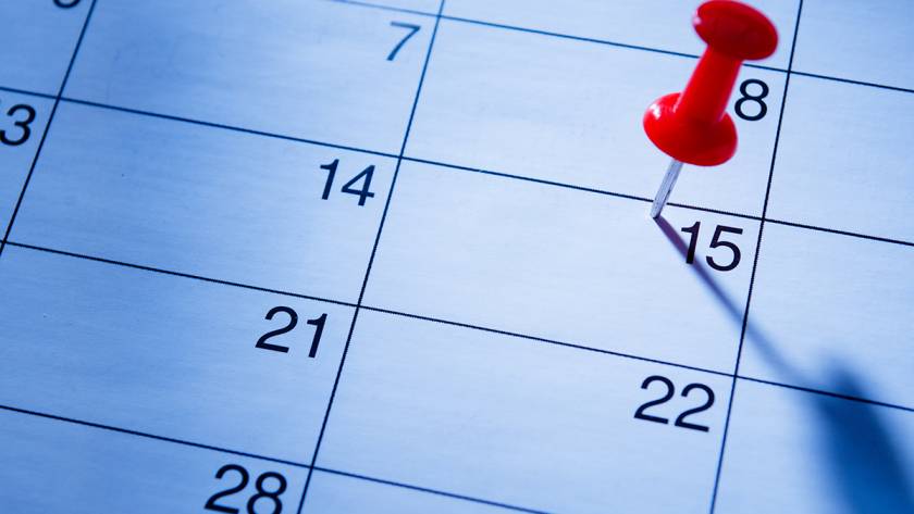 Red pushpin marking date on calendar sheet highlighting the 15th, scheduled event or reminder concept