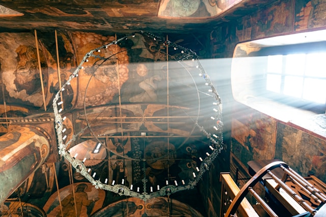 Sunlight streaming through window of Orthodox Church onto ornate ceiling mural in historic building interior