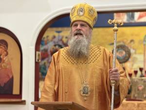 Orthodox priest in ornate gold vestments holding a staff during a religious ceremony in a decorated church setting