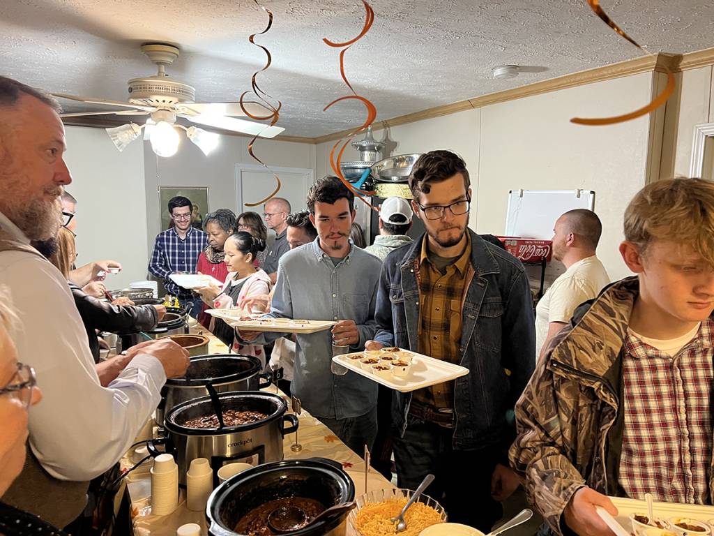 Group of people enjoying a buffet meal at a casual indoor gathering with festive decor