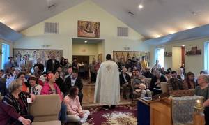 A priest conducting a service in a packed church with attentive congregation members seated and standing
