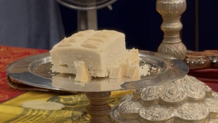 Traditional sweet block on ornate silver tray with decorative items displayed on the side for festive celebration