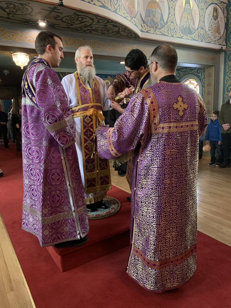 Clergy in ornate purple vestments during a religious ceremony in a beautifully decorated church interior