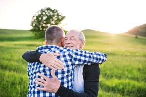 Two people hugging in a sunny field, expressing happiness and connection
