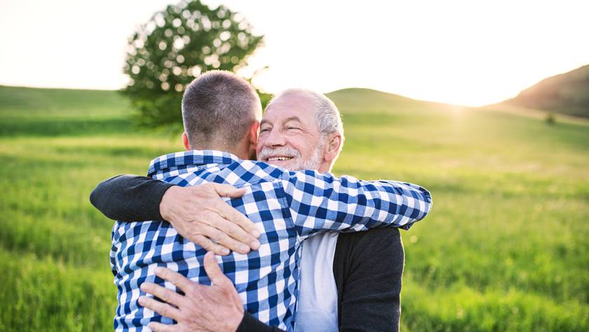 Two people hugging in a sunny field, expressing happiness and connection