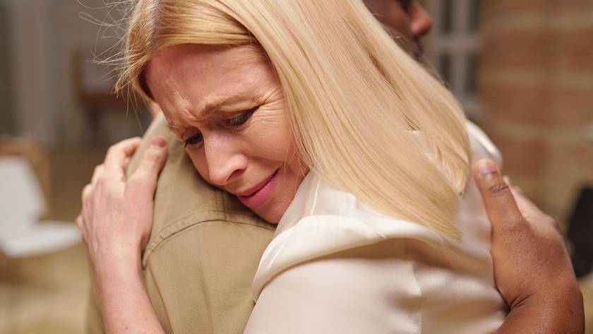 Woman with blonde hair emotionally hugging someone, showing support and comfort in a heartfelt moment