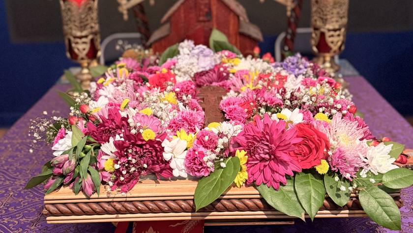 Vibrant floral arrangement with pink, yellow, and white blossoms on a decorative purple tablecloth in a ceremonial setting
