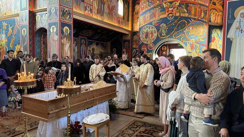 Orthodox Christian funeral service with clergy and mourners in a richly decorated church interior