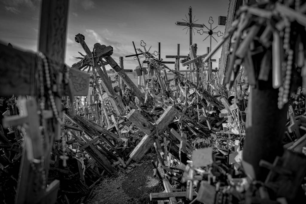 Hundreds of wooden crosses creating a spiritual landscape on a hillside with a cloudy sky in the background