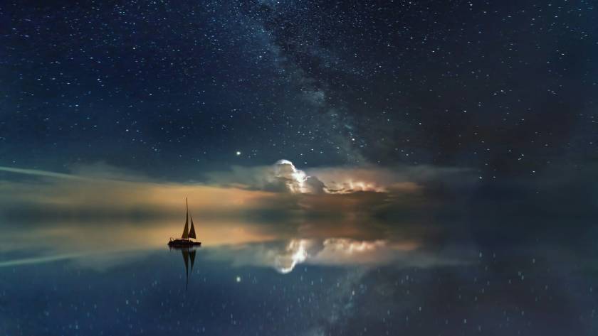 Sailing boat under starry night sky and Milky Way reflections on calm water