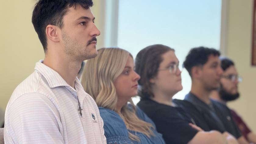 Diverse group of attentive people sitting in a classroom setting, listening intently to a presentation or lecture