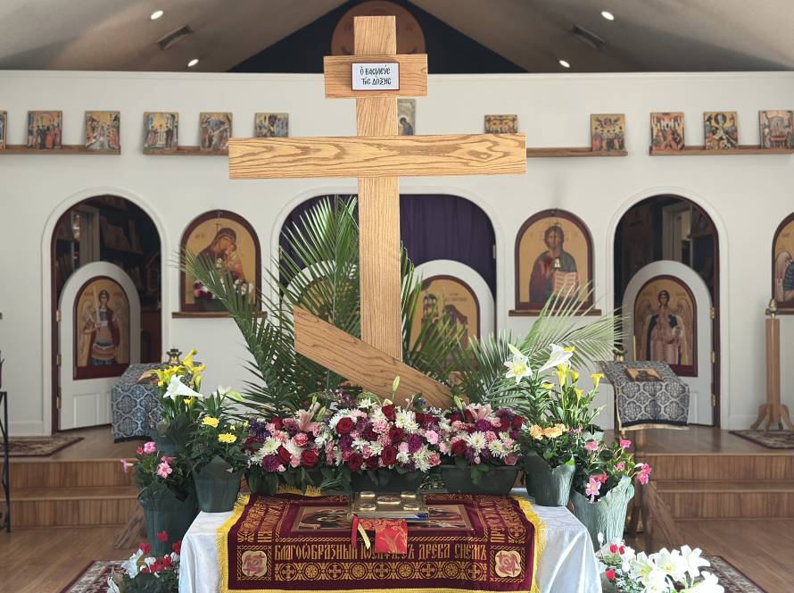 Wooden cross adorned with flowers inside an Orthodox church decorated with icons and religious symbols