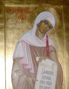 Icon of a woman in religious attire holding a scroll, with glowing halo and golden background