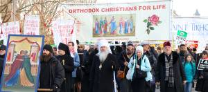Orthodox Christians hold signs and banners at a pro-life march with a religious icon at the forefront