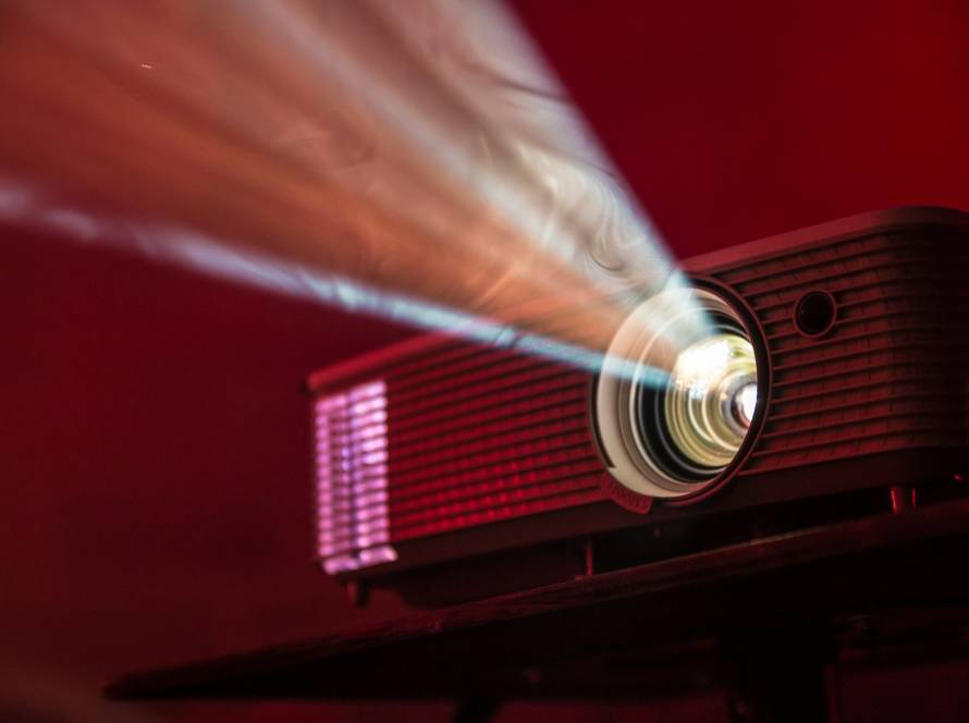 Projector beam illuminating a dark room with red light, showcasing powerful lens and vibrant display effect
