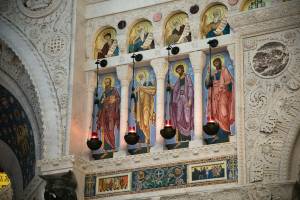 Intricate religious frescoes and ornate carvings in a historic church interior display vibrant saint depictions