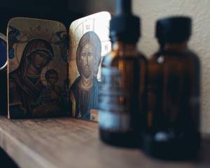 Religious icons beside glass bottles on wooden shelf, serene atmosphere, spiritual decor, home altar setup