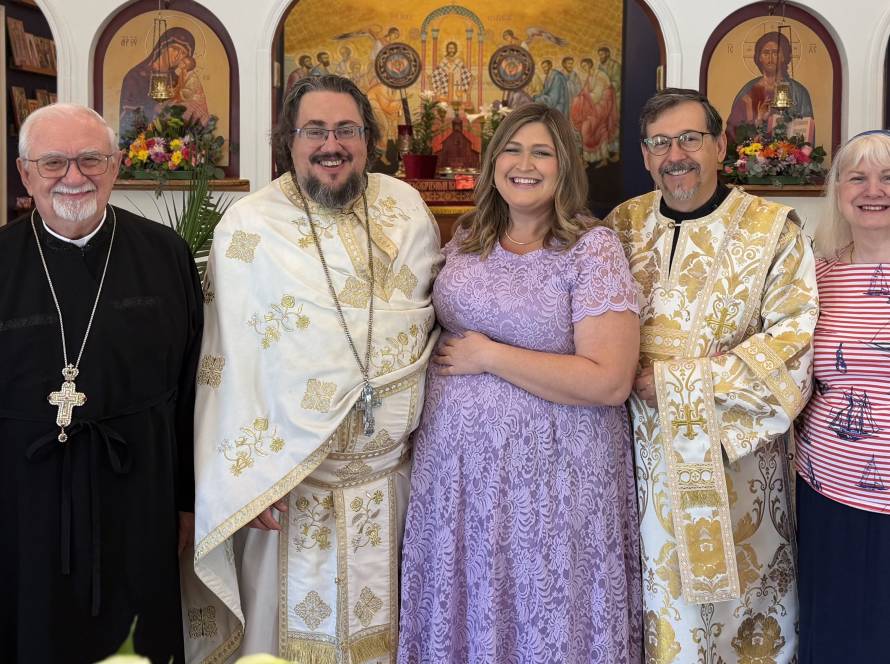 Group posing in a church with icons and flowers in the background, people in ceremonial attire and colorful outfits