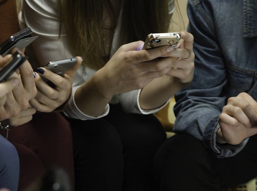 People using smartphones together, focusing on screens, illustrating modern digital connectivity and social interaction