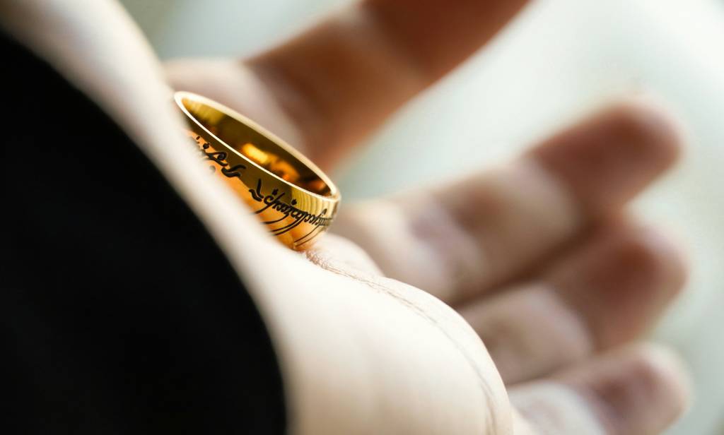 Close-up of a golden ring with inscription, resting on an open hand, symbolizing a mysterious or magical theme