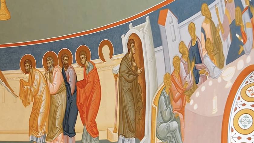 Religious mural depicting apostles with halos in vibrant robes engaged in a gathering indoors