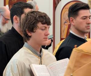 Young men participating in a religious ceremony, holding a book with text, wearing traditional garments in a decorated setting