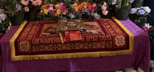 Orthodox religious altar adorned with iconography and surrounded by vibrant flowers