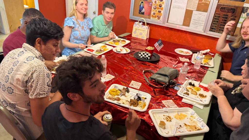 Group of people enjoying a meal together at a table with festive red decorations and American flags