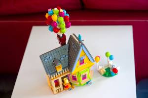 Colorful toy house with balloons on a table, representing childhood creativity and imagination in playful miniatures