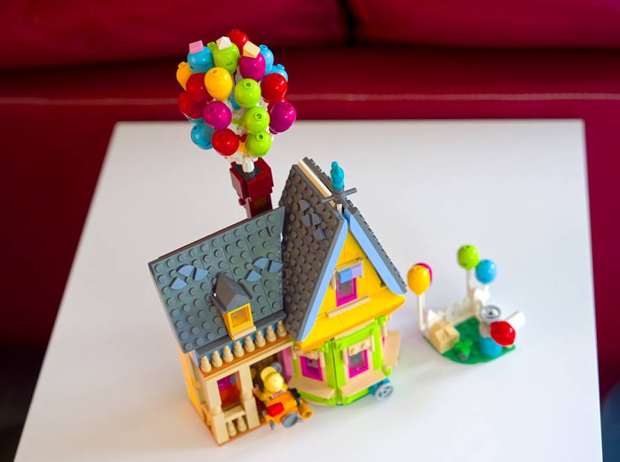 Colorful toy house with balloons on a table, representing childhood creativity and imagination in playful miniatures